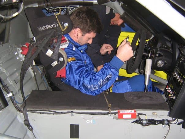 Pilota in tuta da corsa all'interno di un'auto da corsa, mentre si prepara per una gara.