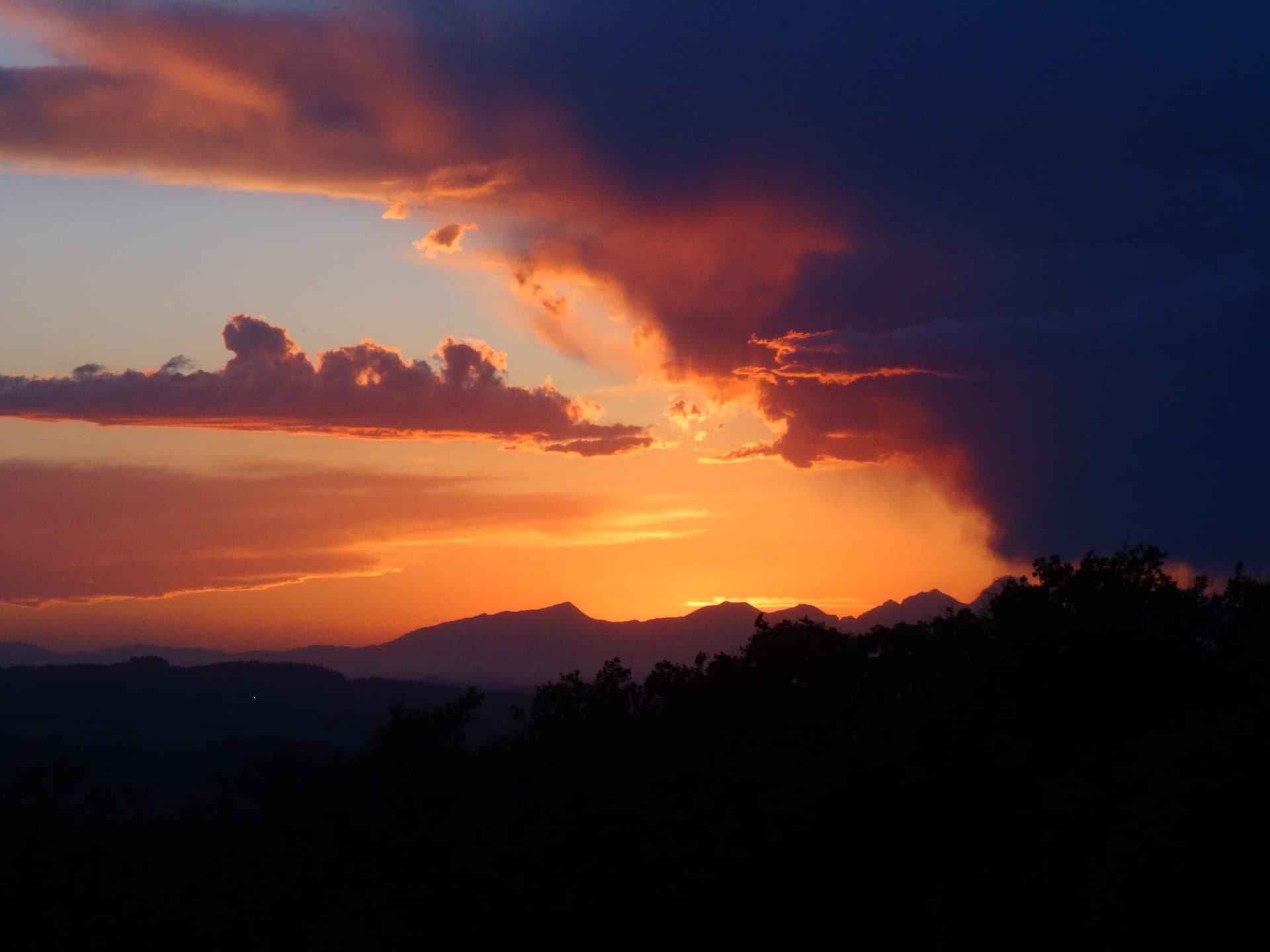 Tramonto mozzafiato sul Chianti, con montagne e nuvole sopra Villa I Barronci Resort & Spa, lusso in Toscana.