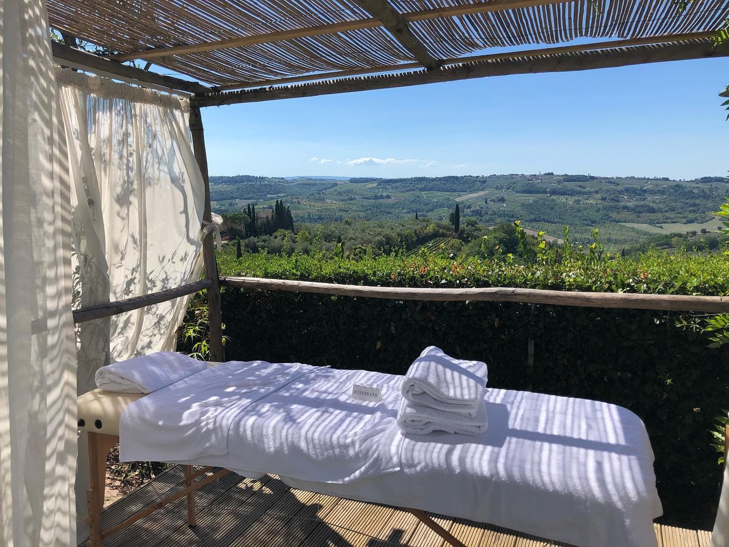 Tavolo da massaggi immerso nel verde toscano, con vista panoramica su colline e vigneti. Atmosfera di relax totale.